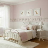 Bedroom with a white metal bed, pink bedding, and a small table with a lamp.