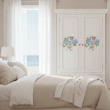 Bedroom with a bed and wardrobe featuring floral designs, large windows with white curtains, and a view of water.