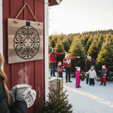 Family in winter clothing standing outside a red building with a wooden circular decoration on the wall.