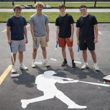 Four young men standing in a parking lot with baseball equipment, posing for a photo.