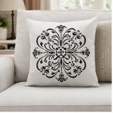 Decorative pillow with black floral pattern on a white background, placed on a light gray sofa.