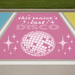 Pink sign with 'this senior's last DISCO' text and disco ball graphic on  parking lot
