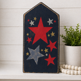 Decorative wall art with red and blue stars on a wooden board against a white wooden panel background.