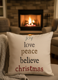 Decorative pillow with Christmas text in front of a fireplace