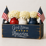 Decorative box with 'God Bless America' text, mason jars with flowers, and American flags.
