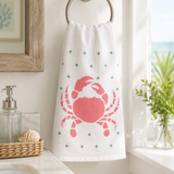 White towel with pink crab design hanging on a towel rack in a bathroom.