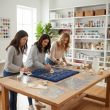 Three women working on a craft project together in a well-lit room with shelves of supplies.