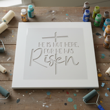 He is not here for he has risen stenciled onto a white sign blank.