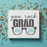 Graduation-themed card with 'you rock GRAD 2026' text and sunglasses graphic on a blue background with gold confetti.