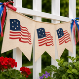 Bunting with American flags hanging on a white lattice background with flowers in the foreground.