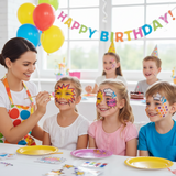 Children with face paint at a birthday party, surrounded by balloons and a 'Happy Birthday!' banner.