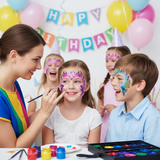 Children with face paint at a birthday party with balloons and a 'Happy Birthday' banner.