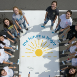'The future is bright' senior parking lot stencil painted in blue and yellow on a white senior parking space.