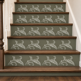 A staircase with dark olive green risers decorated with a repeating white leafy vine pattern, bordered by medium brown wooden steps.