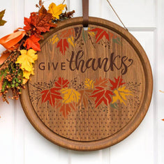 Decorative stencil round sign with 'Give Thanks' and colorful autumn leaves for Thanksgiving décor.
