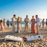 Group of people on a beach with cornhole boards and ocean view