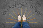 Person standing on pavement that has been stenciled with 'The Future is Bright' text.
