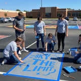 Text 'The Sky is the Limit' stenciled on pavement with matching stencil.