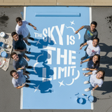 High School Kids Standing around a parking space that has been painted with the "Sky is the Limit" senior parking space stencil.