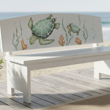 Sea Turtles Stencil painted onto a white bench along the boardwalk of a beach.
